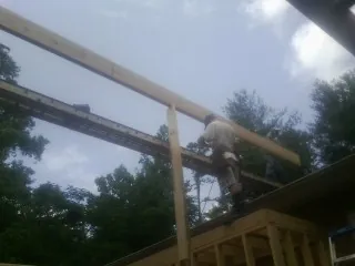 Carpenter setting a ridge beam over a new addition frame — Ice Dam Removal by Roofing Brothers in Desoto