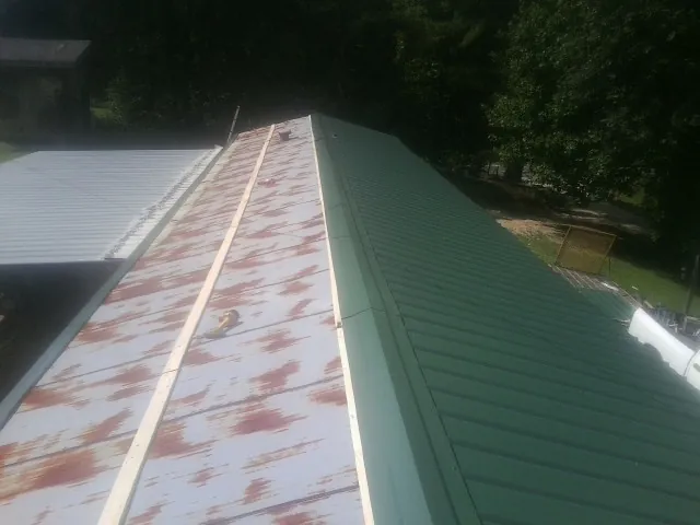Old rusted panels beside newly installed green metal roofing — Wind Damage Roof Repair by Roofing Brothers in Desoto
