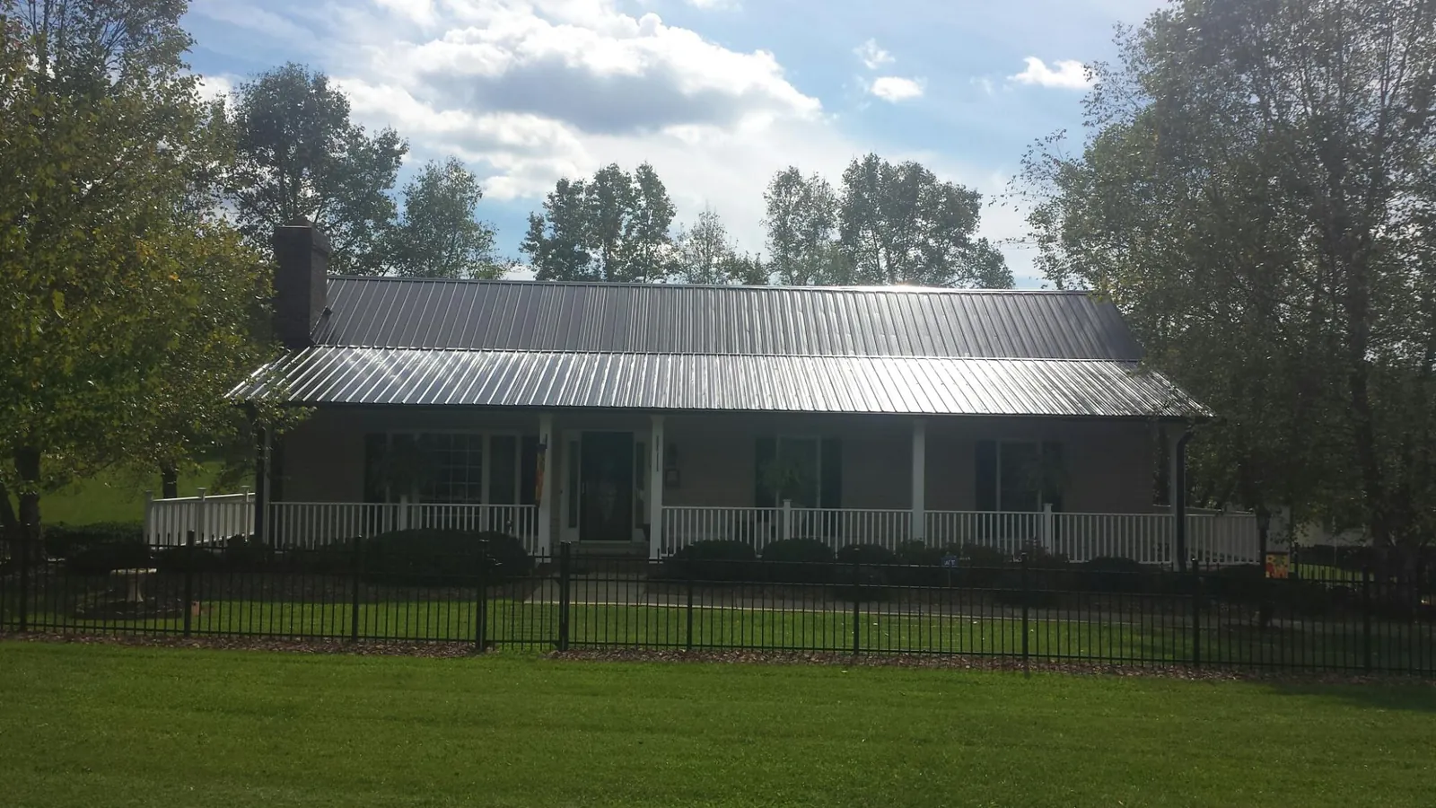 Gray metal roof on a brick ranch with a full width front porch — Gutter Guard Installation work by our crew in Desoto