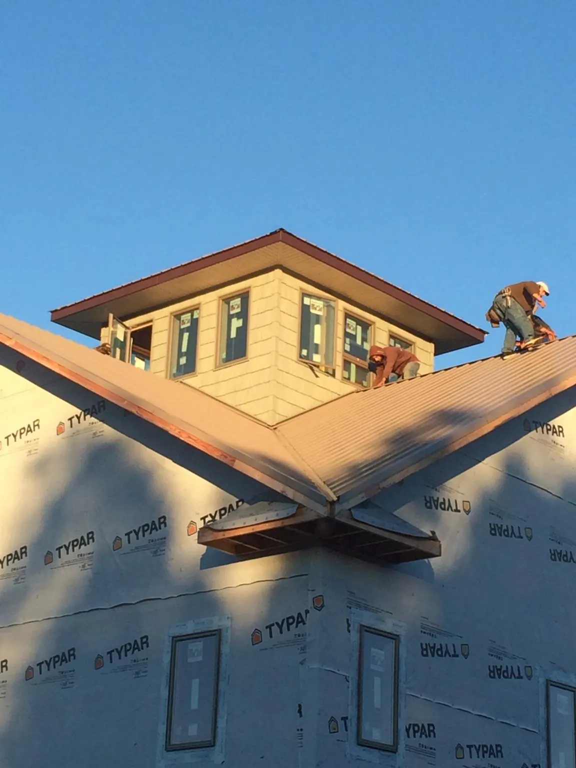 Roofers working around a rooftop cupola on a new metal roof at sunset — Roof Waterproofing in Desoto by Roofing Brothers